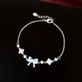 Close-up of silver-tone bracelet with light blue bow and flower zircon charms - Silver-Blue