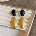 Nahaufnahme von geometrischen Vintage-Ohrsteckern mit strukturierter Gold- und Holzoptik - Gold, Schwarz