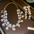 Makrodetail eines Goldschmucksets mit funkelnden Tropfen- und runden Strasssteinen. - Halskette Ohrring Schmuck / Gold