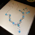 Gedetailleerde weergave van blauwe bloem en zilveren bladhanger ketting en oorbellen - Ketting En Oorbellen Set / Zilver-Groen