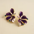 Detailed macro view of purple enamel flower stud earrings with shimmering blue rhinestones - Purple