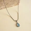 Vue détaillée du pendentif goutte d'eau en résine bleu clair sur chaîne acier - Argent-Bleu