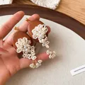 Detailed view of vintage elliptical wood earrings with beaded flower and pearl tassels - White/Brown