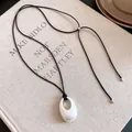 Nahaufnahme einer schlichten schwarzen Kordelkette mit einem stilvollen mattweißen Oval-Anhänger - Matt Silber