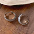 Elegante retro oorringen met marmeren druppelolie textuur op een houten oppervlak - Zilveren Basis Grijze Marmeren Textuur