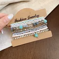 Détail en gros plan du lot de bracelets bohèmes avec perles de verre et strass brillants - Rose Bleu Gris