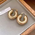 Elegante klobige goldene Creolen mit gerippter Textur in einer stilvollen Schmuckschatulle - Runder Texturstil / Ohrringe mit Scharnier-Gold