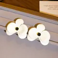 Detailaufnahme von weißen Blumenohrsteckern mit eleganten schwarzen Kristallzentren - Stil mit Silber-Ohrstecker / Weiß