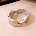 Primer plano de un elegante brazalete ovalado torcido plateado con diseño minimalista - Plateado