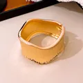 Vista detallada de un brazalete dorado distorsionado con textura vertical elegante - Dorado