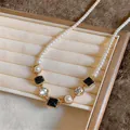 Detailopname van een elegante parelketting met zwarte vierkante edelsteenaccenten - Goud-Wit-Zwart