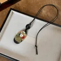 Gedetailleerd overzicht van een etnische houten ketting met knopen en groene kwast - Knoop Kwastje Ellips Hanger (4#)