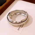 Détail d'un bracelet jonc épais argenté poli avec un design organique ondulé pour femme. - Argent