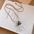 Gros plan d'un collier avec pendentif en bois et glands de perles blanches. - Collier-Café-Gris-Blanc