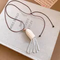 Détail en gros plan du collier avec pendentif en bois et glands en perles blanches - Collier-Marron-Blanc