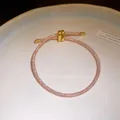 Detailopname van een roze kristallen armband met gouden schuifsluiting. - Roségoud