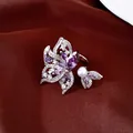 Detalle macro de anillo chapado en oro de 18k con alas de mariposa de circón púrpura y perla - Plateado