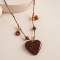 Close-up of a vintage leopard print heart pendant on a brown braided cord necklace. - Brown Necklace (Heart Style)