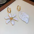 Primer plano de aros dorados asimétricos con flor y hoja de esmalte blanco elegante - Asimétrico Flor y Hoja (HE35536) / Blanco