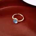 Primer plano de un elegante anillo abierto bañado en oro con una piedra de circón azul - Abierto Ajustable / Dorado-Azul