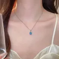 Nahaufnahme einer silbernen Halskette mit blauem Zirkon-Blumenanhänger an einem Modell - Kette Ohne Anhänger / Blau
