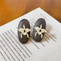 Macro view of vintage style oval wooden stud earrings with creamy white orchid flowers - Coffee-White