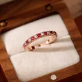Détail macro d'une bague élégante en or rose sertie de zircons rouges et blancs - Style Ouvert Rond / Or Rose-Rose