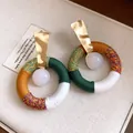 Detailaufnahme der schicken, farbenfrohen Baumwollfaden-Ohrringe mit weißer Harzperle - Gold Mehrfarbig