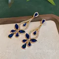 Elegante goldfarbene Hängeohrringe mit tiefblauen Wassertropfensteinen und glitzernden Kristallen. - Blau