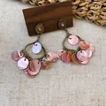 Close-up detail of vintage bronze chandelier earrings featuring iridescent pink shell tassels - Gold-Pink