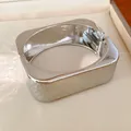 Primer plano de un brazalete rectangular plateado con textura metálica arrugada - Plateado