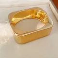 Primer plano detallado de un brazalete rectangular dorado de textura martillada. - Dorado