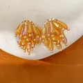 Close-up macro shot of elegant amber glass tassel stud earrings with golden accents - Tassel Studs / Gold with Coffee
