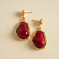 Detail shot of vintage irregular geometric earrings with red resin and gold metal. - Red