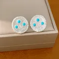 Close-up van zilveren ronde oorknopjes met blauw harsbloemontwerp. - Bloemvorm / Zilver/Blauw