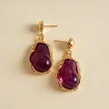 Detailed macro shot of vintage gold earrings featuring irregular purple resin pendants - Purple