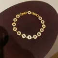 Nahaufnahme eines vergoldeten Armbands mit antiken Münzgliedern und funkelnden Zirkonen - Zirkonia Münz Stil / Gold