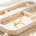 Gros plan d'une bague vague minimaliste en acier titane doré sur plateau velours - Or