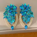 Gros plan détaillé sur de grandes boucles d'oreilles fleur en cristal bleu scintillant - Bleu