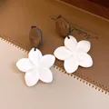 Detailopname van retro oorbellen met houten knopjes en witte schelpbloem hangers - Schelp Bloem Ster Stijl