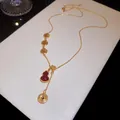 Vue macro détaillée d'un collier plaqué or 18 carats avec pendentif calebasse rouge - Or avec Rouge et Blanc