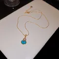 Gros plan d'un collier pendentif hulu plaqué or avec pierre turquoise sur boîte blanche. - Or avec Bleu