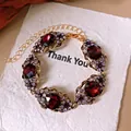 Detailansicht eines Vintage-Armbands im Palaststil mit roten Kristallen und lila Strass. - Armband / Gold-Lila