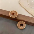Primer plano detallado de pendientes redondos vintage dorados con centro de efecto mármol - Estilo de borde dorado redondo torcido / Naranja