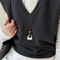 Gros plan d'un collier avec pendentif géométrique en argent brossé et perles sur un modèle. - Brushed Square