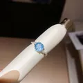 Detailopname van een vergulde ring met gefacetteerde blauwe zirkoon en spiraalband - Stijl 2 (HR3923)