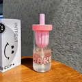 Detail view of a pink tea infuser glass water bottle next to its smile packaging box - 600ml / Pink