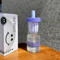 Detail view of a purple tea infuser glass cup with its minimalist smiley face packaging. - 600ml / Purple
