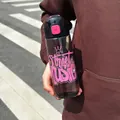 Person holding a stylish 'Street Music' plastic sports water bottle outdoors - 700ml / Black Pink