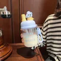 Detail view of a portable cartoon glass water bottle featuring a straw and cute character lid - 500ml / Blue